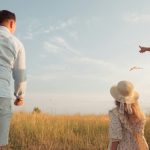 A family in a field flying a kite under a clear blue sky