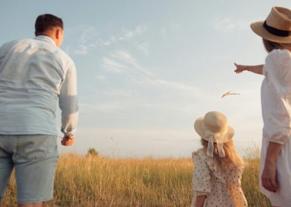 A family in a field flying a kite under a clear blue sky